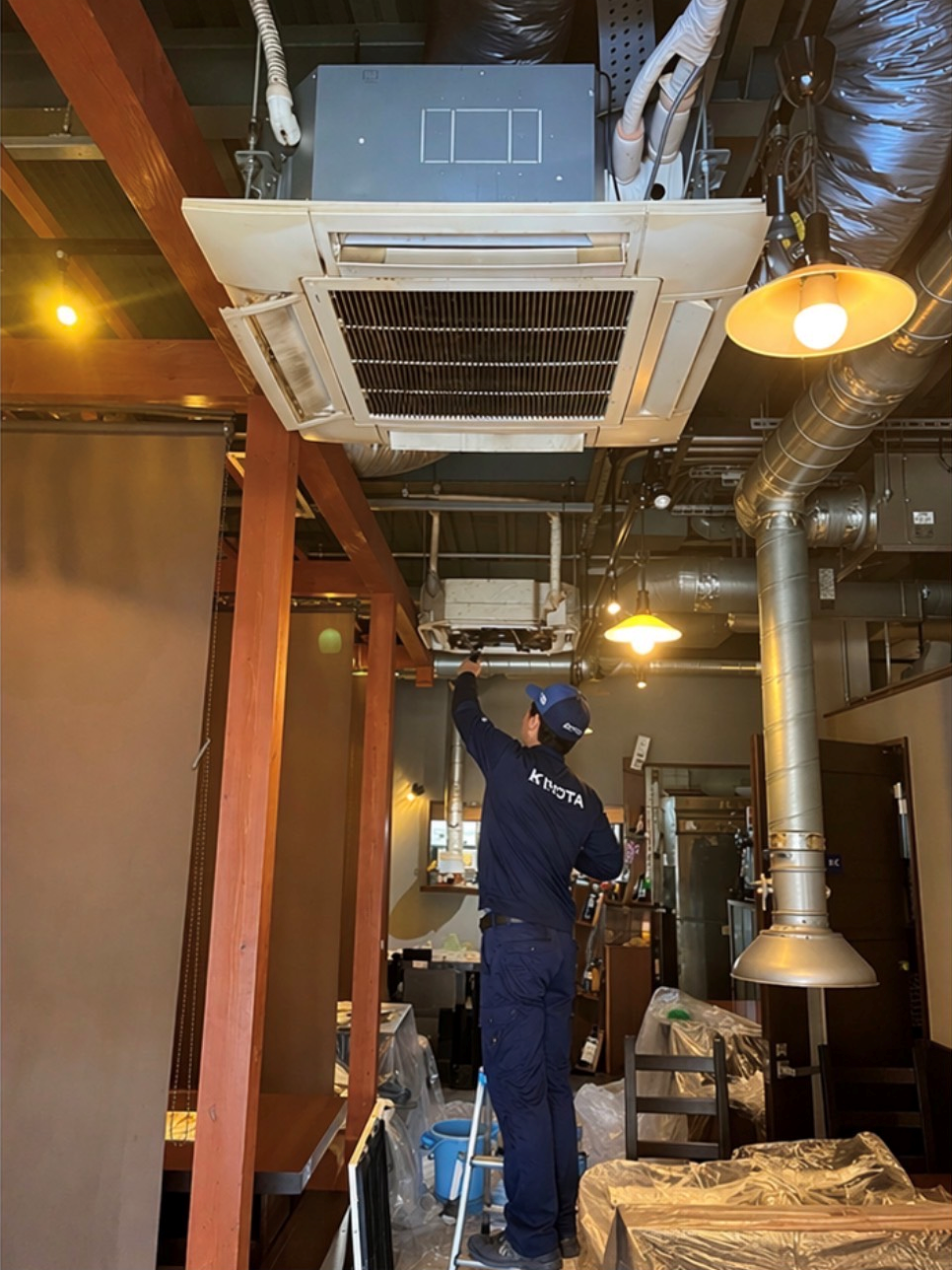 大阪の店舗で業務用天井エアコンを清掃するスタッフの作業風景